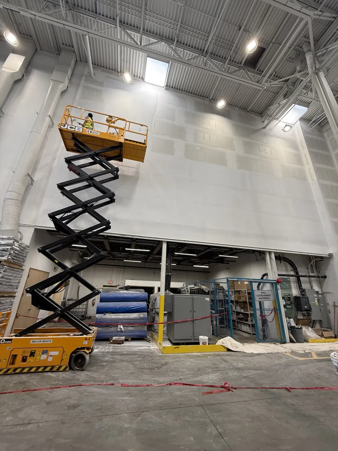 High-access commercial painting with a scissor lift at an industrial facility in Delta, BC